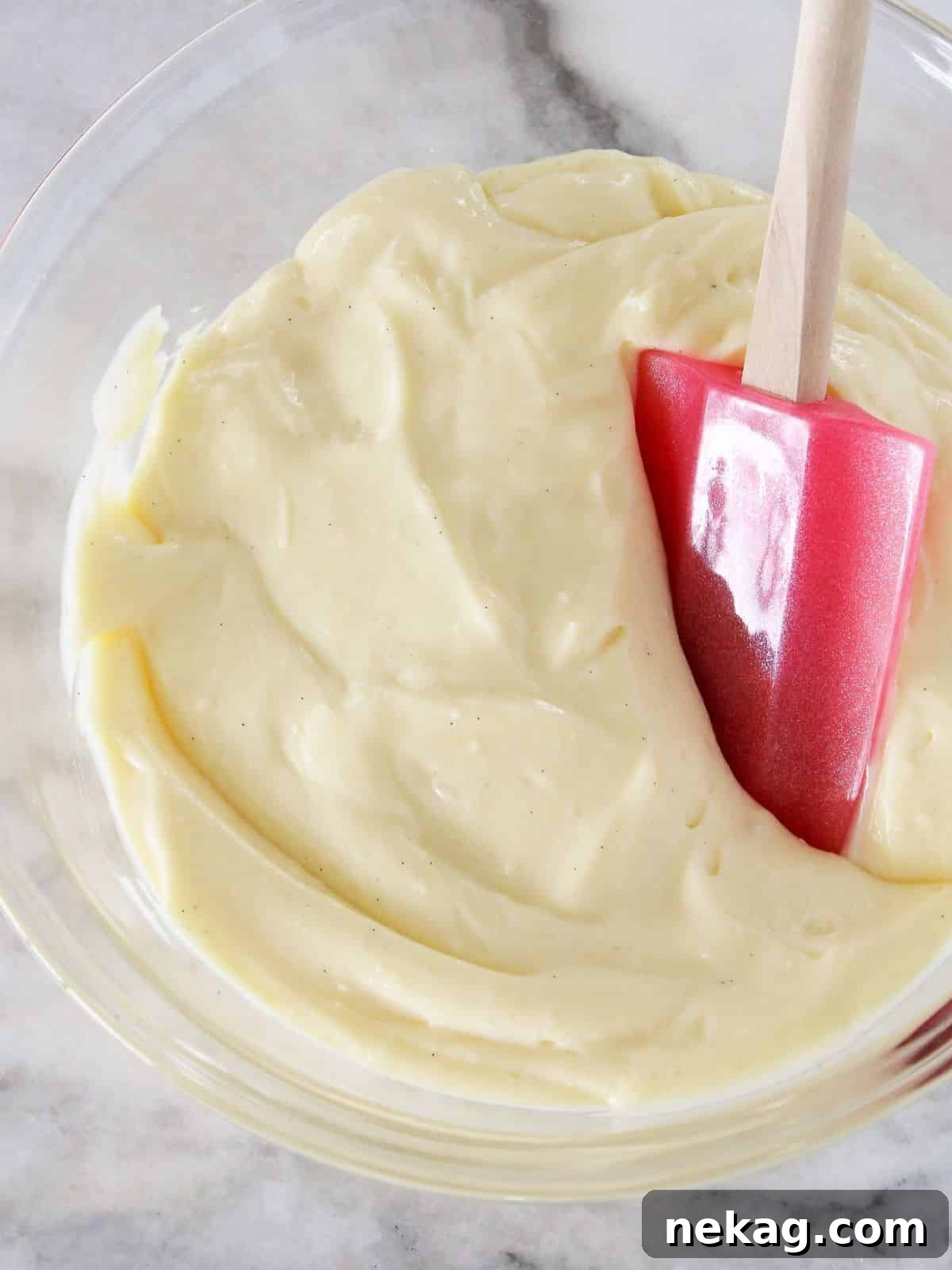 Silky vanilla bean pastry cream on a marble counter, ready for use.