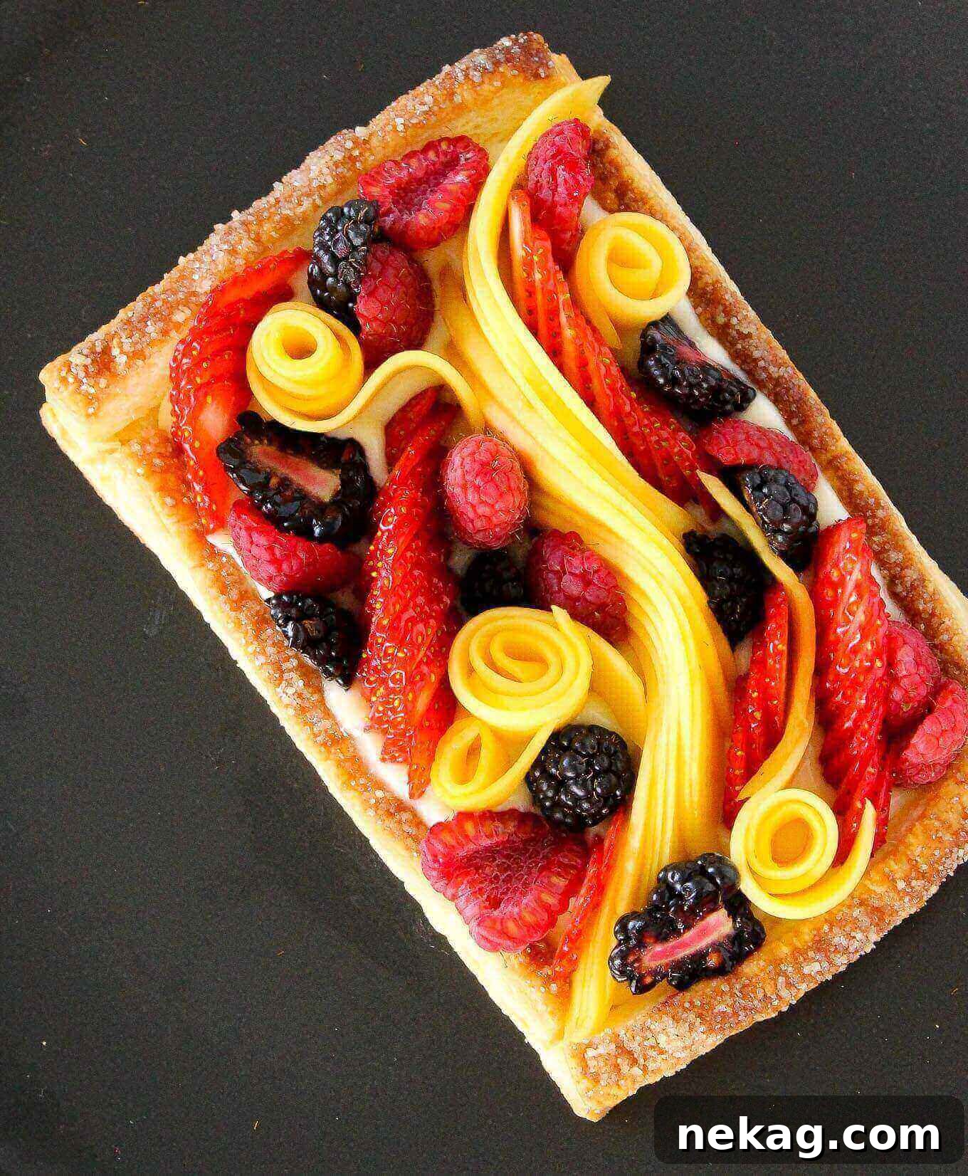 Vibrant Fruit Puff Pastry 4 Puff pastry tart with decorative fruit including fresh berries and sliced mango along the center, ready to be served.