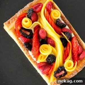 Puff pastry fruit tart close-up on a black plate.