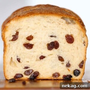 Close-up of a sliced sourdough raisin bread loaf, highlighting the generous distribution of juicy raisins throughout.