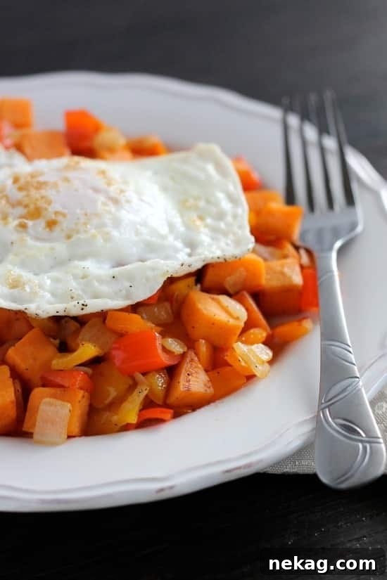Sweet Potato Hash served on a plate, topped with a perfectly fried egg and garnished with fresh herbs