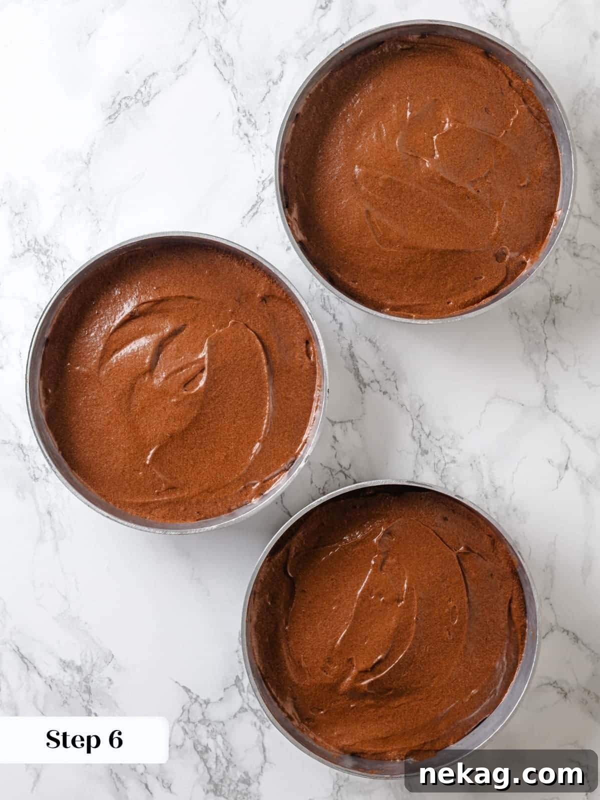 Sinfully Rich Chocolate Cake 13 Rich chocolate cake batter is neatly portioned into three prepared baking pans, poised and ready to be placed into the preheated oven.