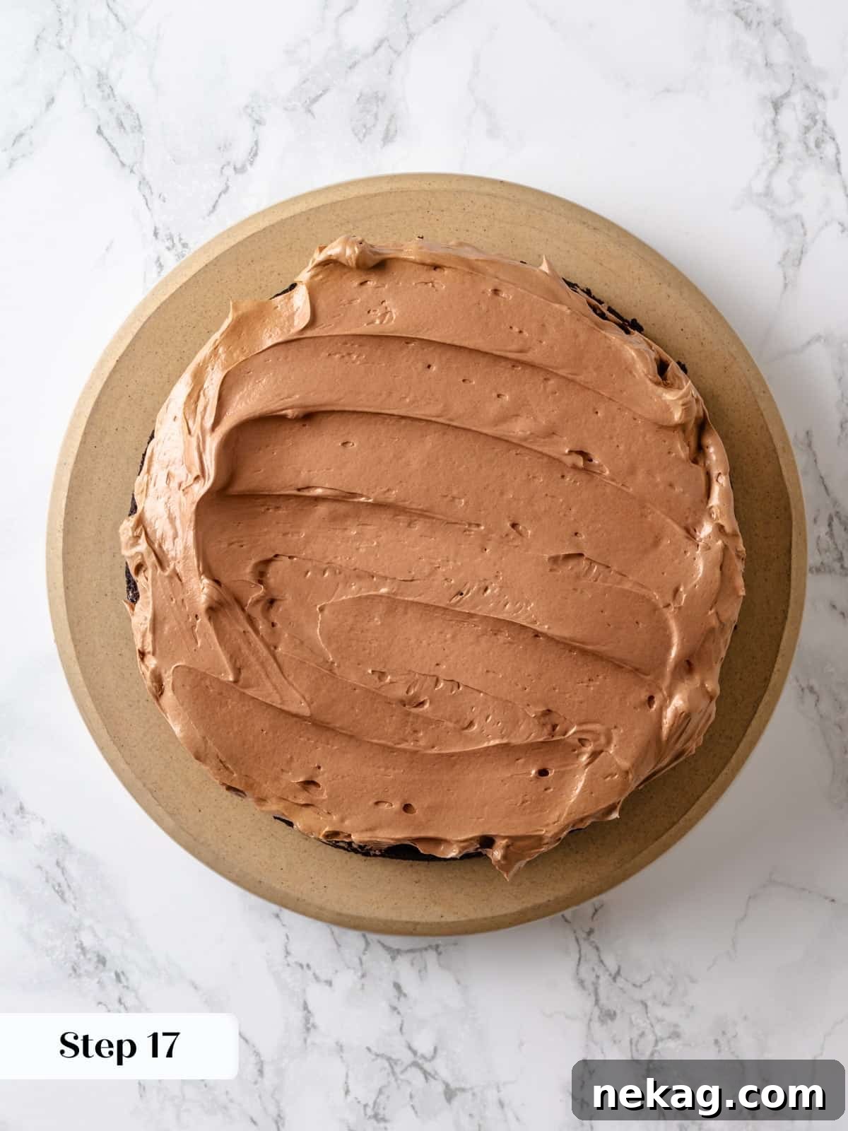 Sinfully Rich Chocolate Cake 23 A generous amount of smooth buttercream is skillfully spread across a cake layer using an offset spatula, ensuring even and consistent coverage.