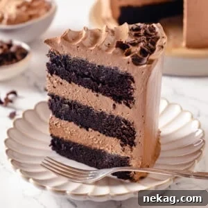 A detailed close-up of a chocolate cake slice, perfectly highlighting the smooth, velvety buttercream between its moist, dark cake layers.