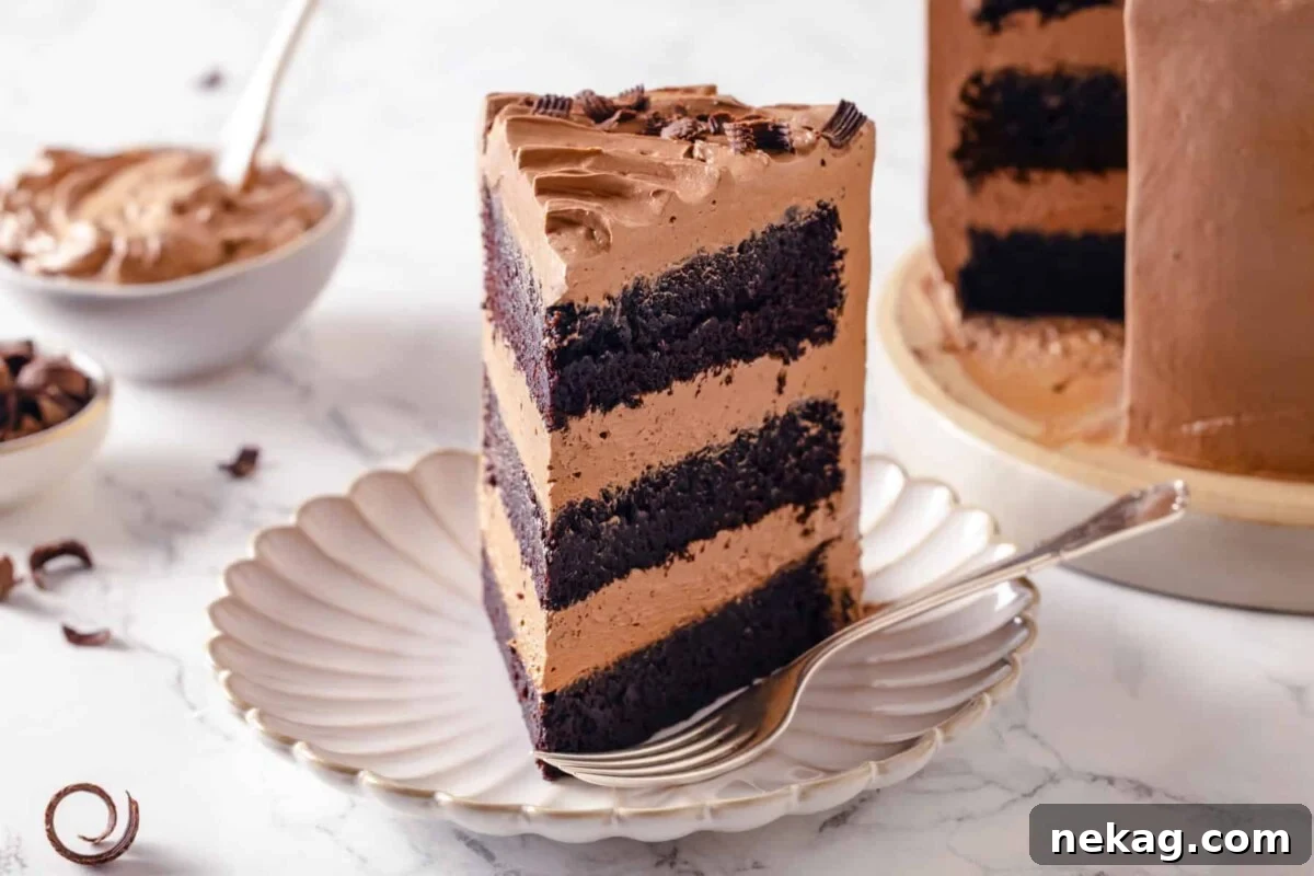 Sinfully Rich Chocolate Cake 5 A perfectly portioned slice of Devil’s Food Cake, featuring distinct layers of moist chocolate cake and smooth buttercream, is presented on a white plate with a fork poised beside it.