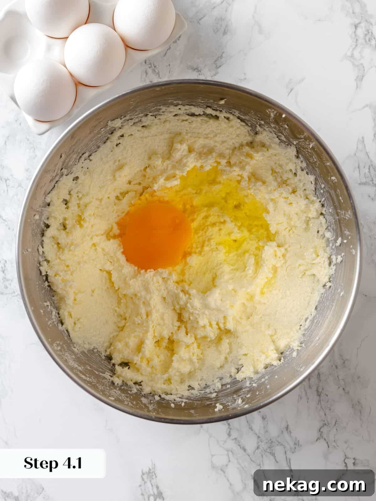 Sinfully Rich Chocolate Cake 8 Whole eggs are gradually mixing into the creamed butter and sugar mixture, starting the emulsion process for the cake batter.