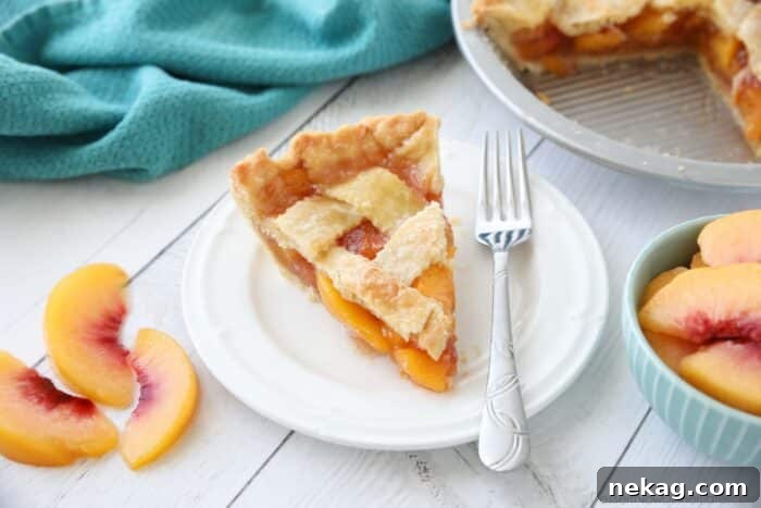 A close-up slice of homemade peach pie with a delicate, golden crust and juicy filling.