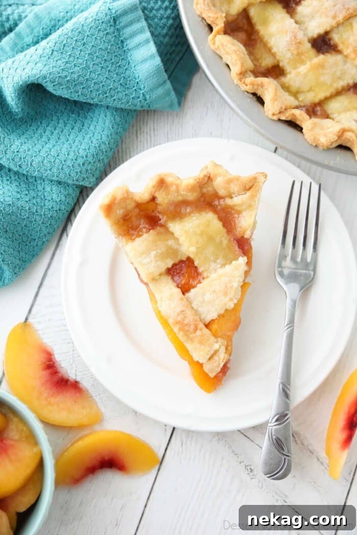 A perfect slice of peach pie on a plate, featuring a perfectly set filling and a golden-brown bottom crust.