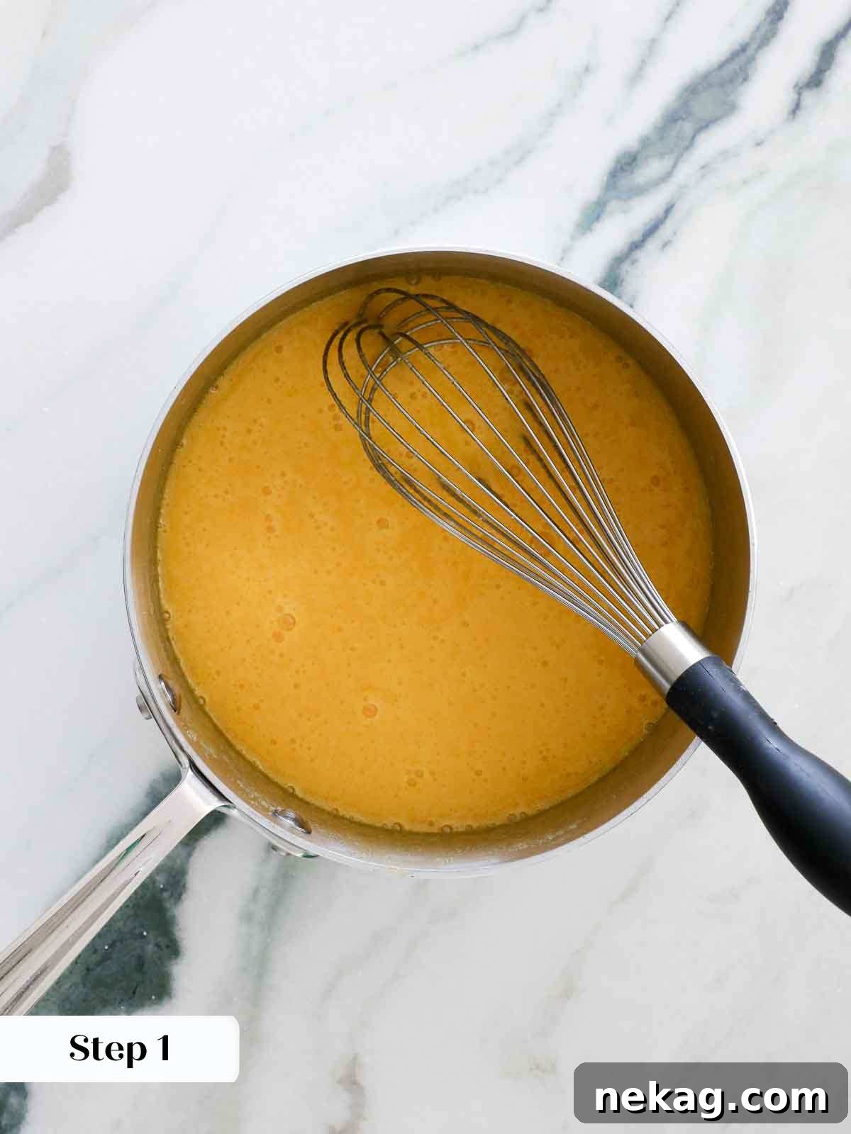 Close-up of whisked eggs and egg yolks in a saucepan, showing a smooth, uniform mixture.