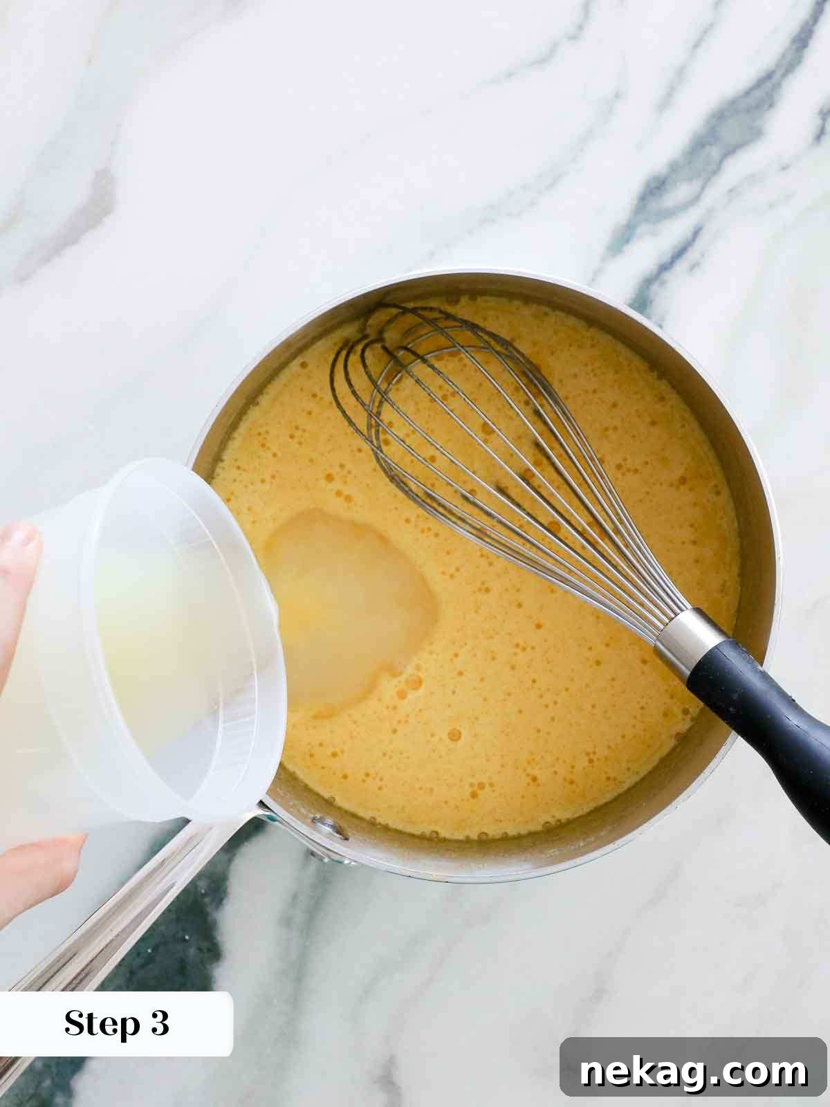 Hand slowly pouring fresh lemon juice into a saucepan with whisked sugar and eggs for lemon curd.