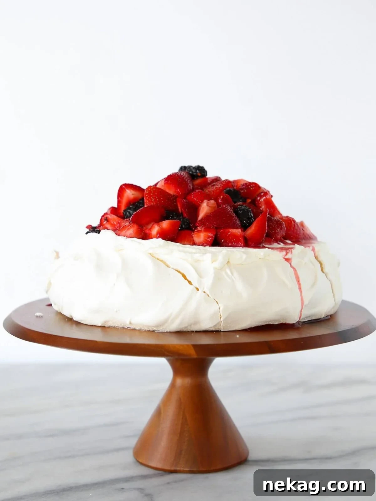 Lemon berry pavlova cake against a white backdrop.