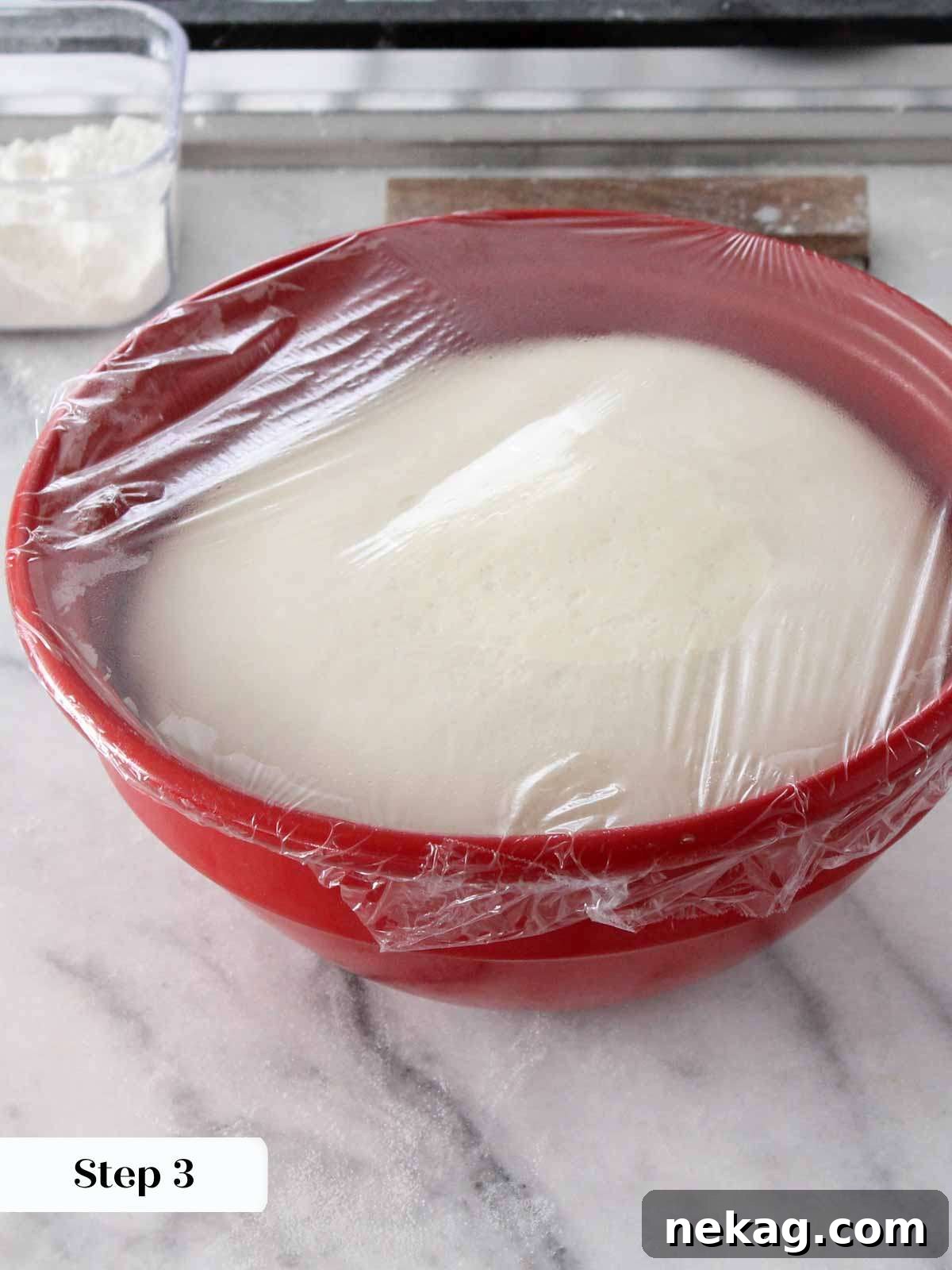 Pillowy Soft Brioche Buns 4 Proofed brioche dough resting in a red bowl, doubled in size and ready for shaping.