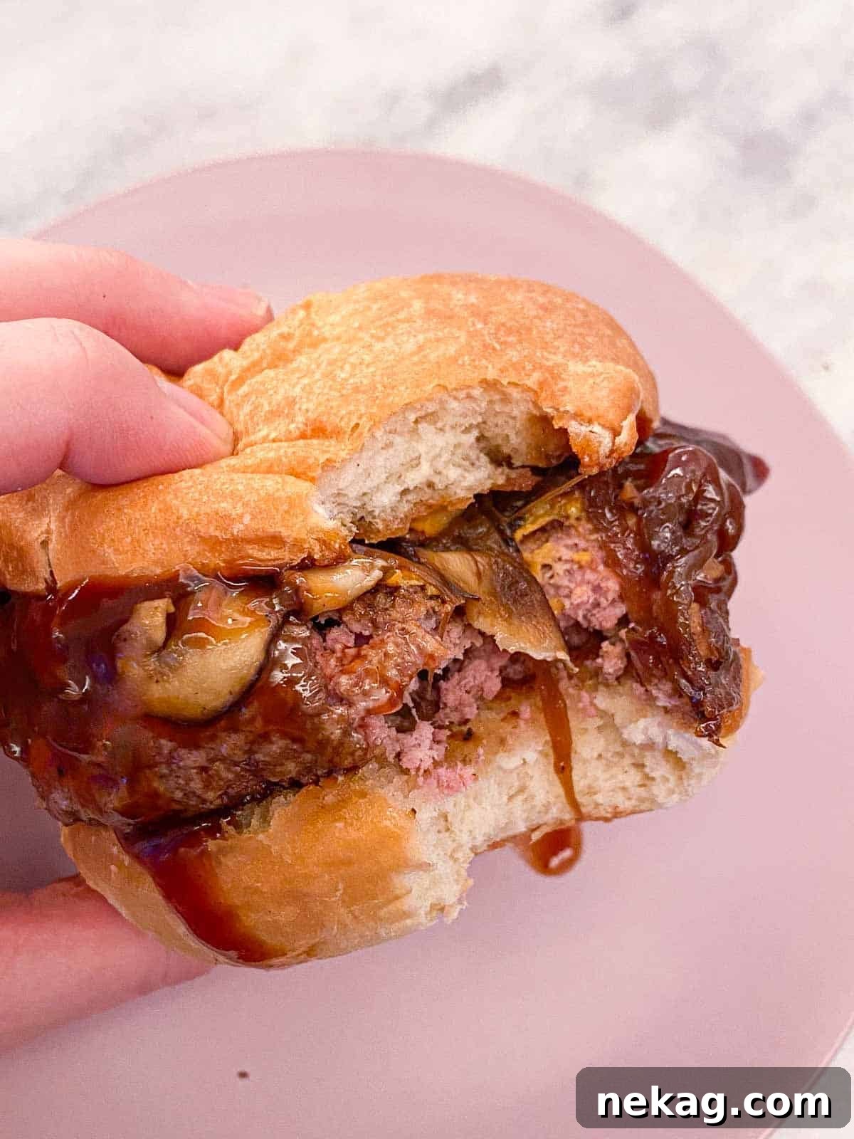 Pillowy Soft Brioche Buns 7 A hand holding a delicious burger nestled in a perfectly baked brioche bun.