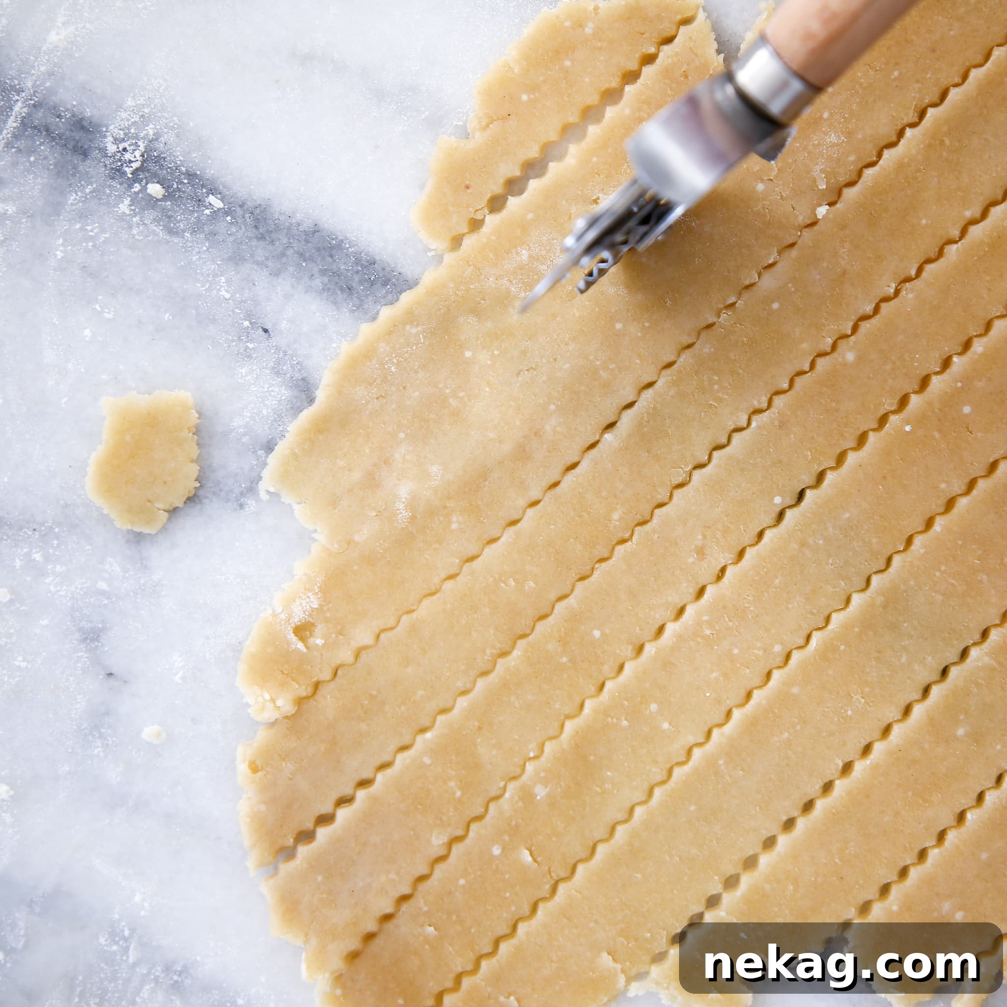 A fluted cutting wheel creating decorative strips from an almond flour pie crust.