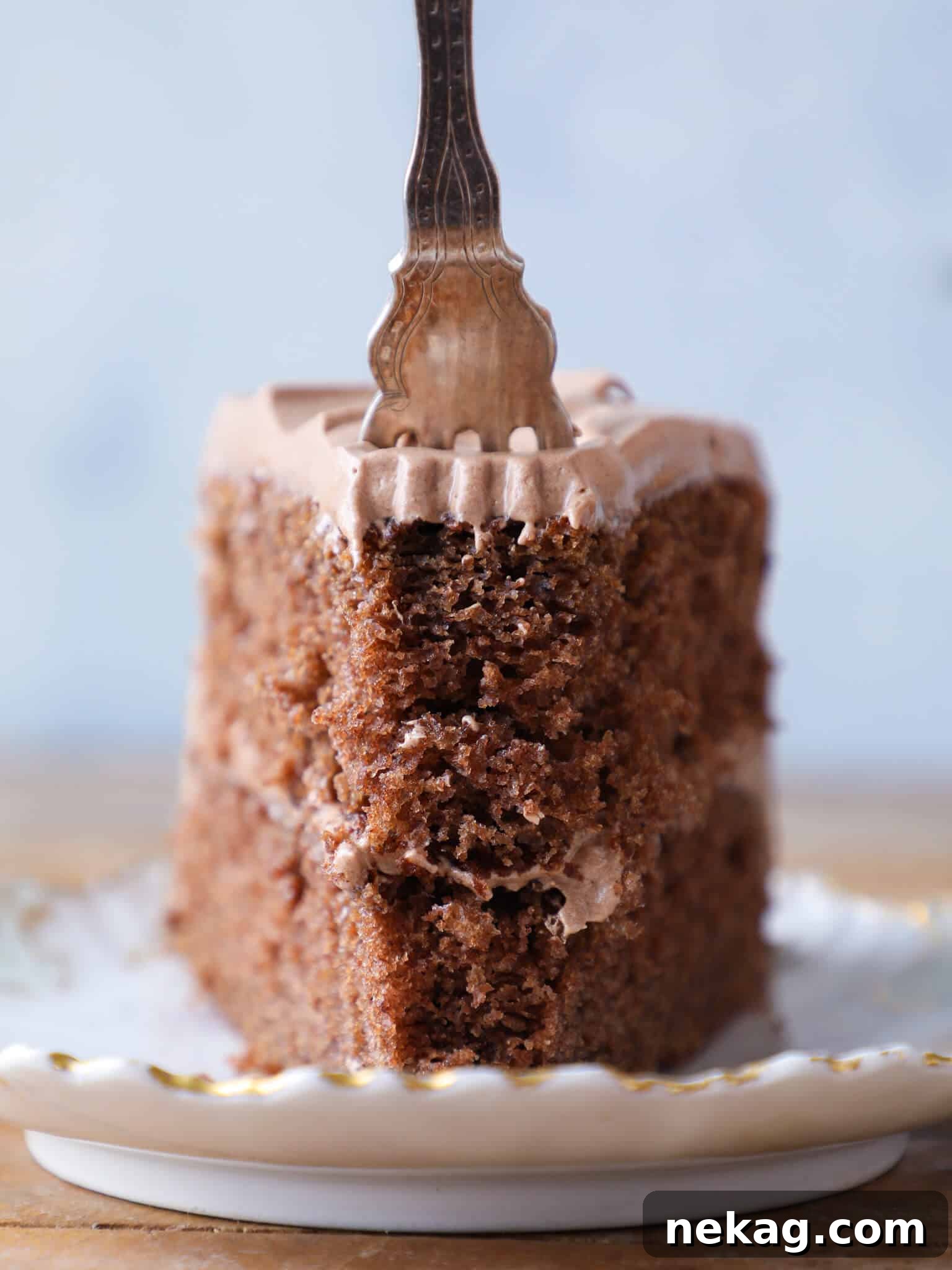 Sinful Chocolate Fudge Delight 2 A delectable slice of old-fashioned chocolate fudge cake with a piece on a fork, showcasing its rich, fudgy texture and creamy icing.