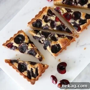 A beautifully baked Cherry Almond Tart, sliced and ready to serve on a rustic wooden board.
