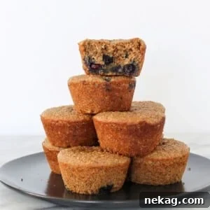 A banana protein muffin with one bite taken, stacked with others to show soft inside texture.