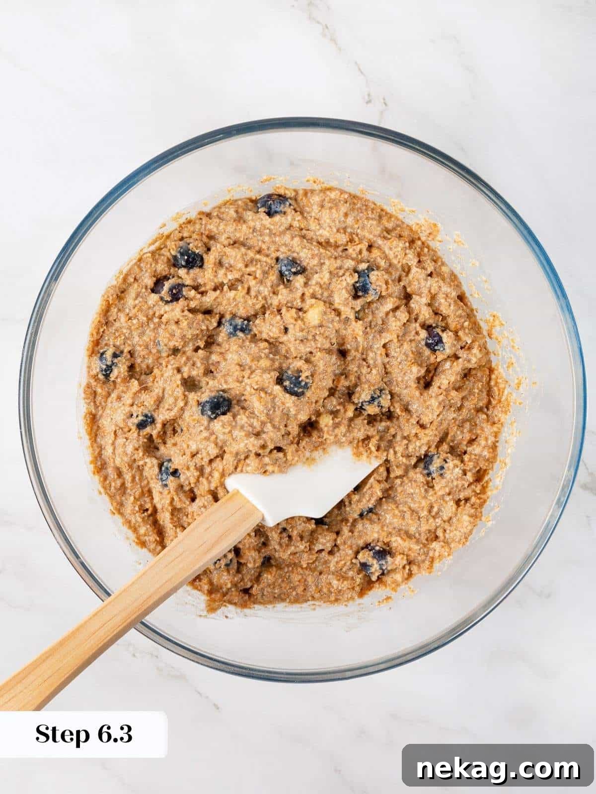 Protein-Powered Banana Muffins 10 A close-up of thick, lumpy muffin batter, rich with visible blueberries and well-hydrated bran, perfectly mixed and ready for baking, showcasing ideal consistency.