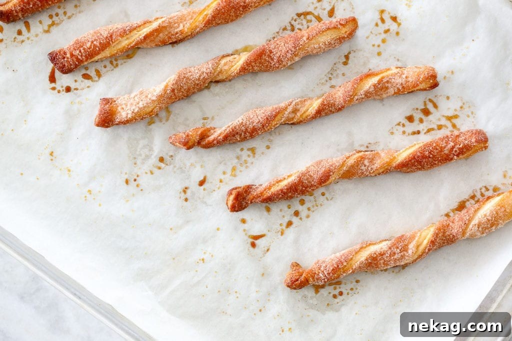Golden brown Cinnamon Sugar Twists on parchment paper, fresh out of the oven