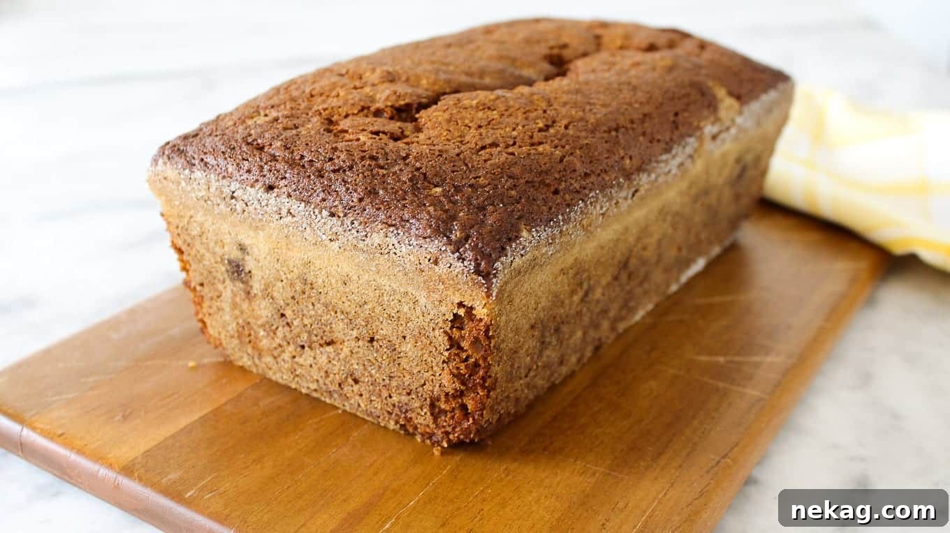 Spiced Pumpkin Delight 3 A whole pumpkin bread loaf, unsliced, resting on a wooden board.