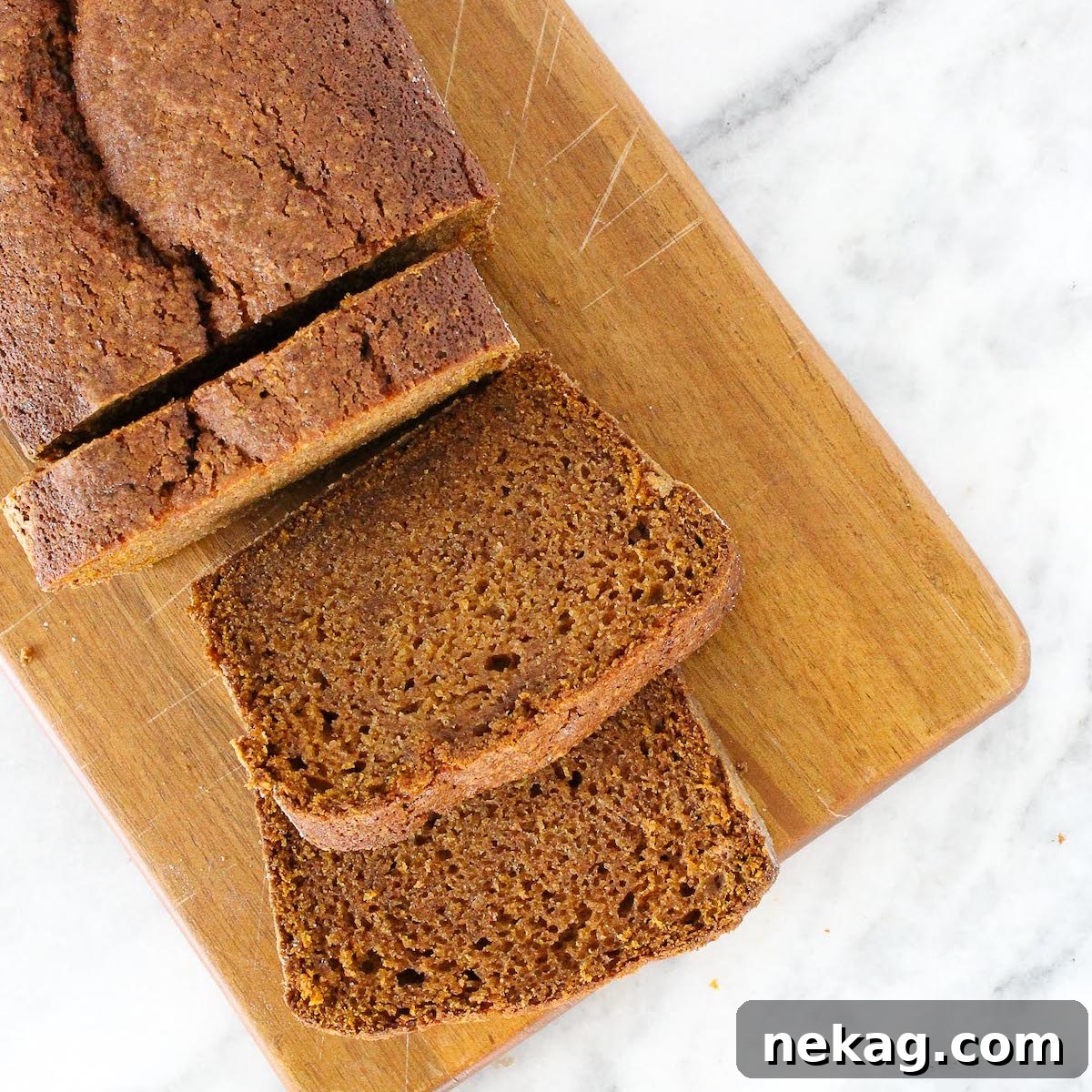 Spiced Pumpkin Delight 5 Perfectly sliced pumpkin bread arranged on a wooden board on a marble countertop.