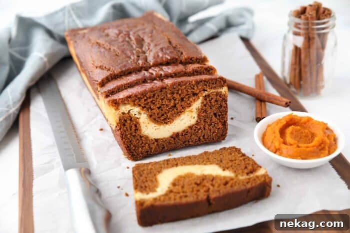 Swirled Pumpkin Cream Cheese Bread 11 A loaf of pumpkin bread with a few slices cut, showing a ribbon of cream cheese in the center.