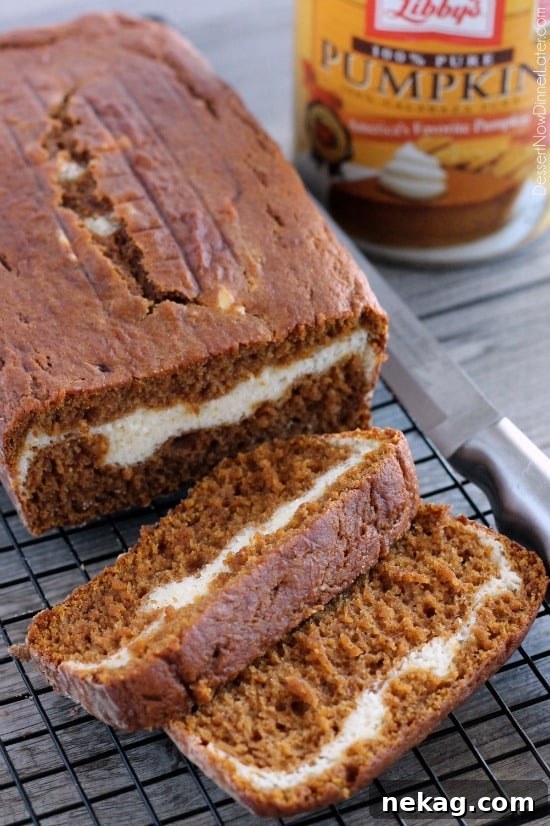 Swirled Pumpkin Cream Cheese Bread 13 Pumpkin Cream Cheese Bread on a wire rack with a couple of slices cut off the end.