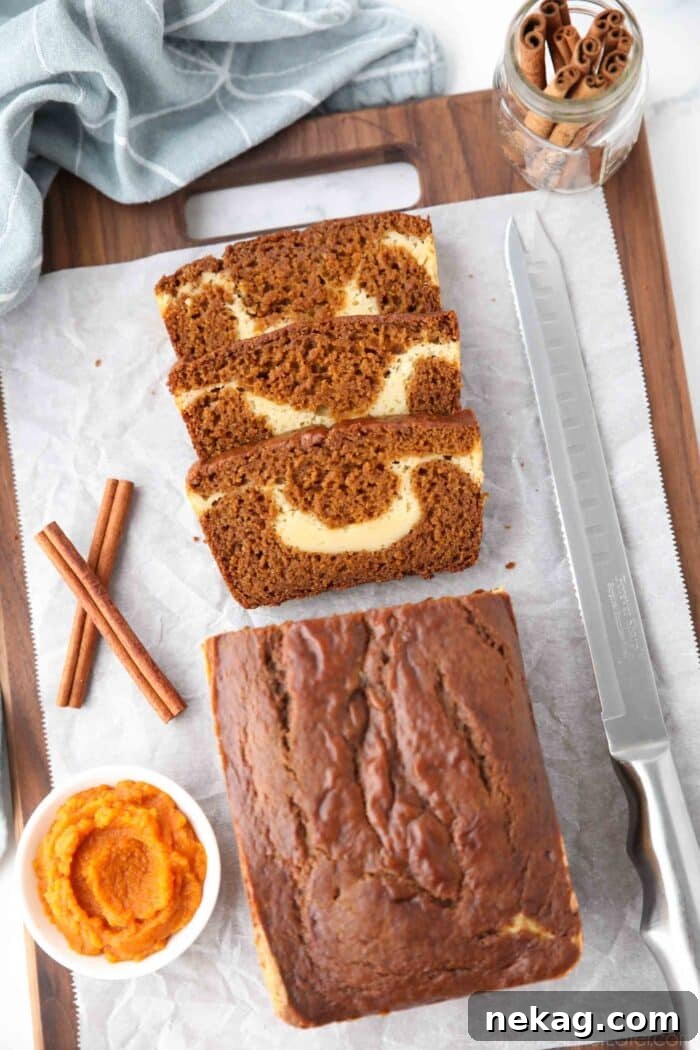 Swirled Pumpkin Cream Cheese Bread 3 A loaf of pumpkin bread with a few slices cut, showing a ribbon of cream cheese in the center.