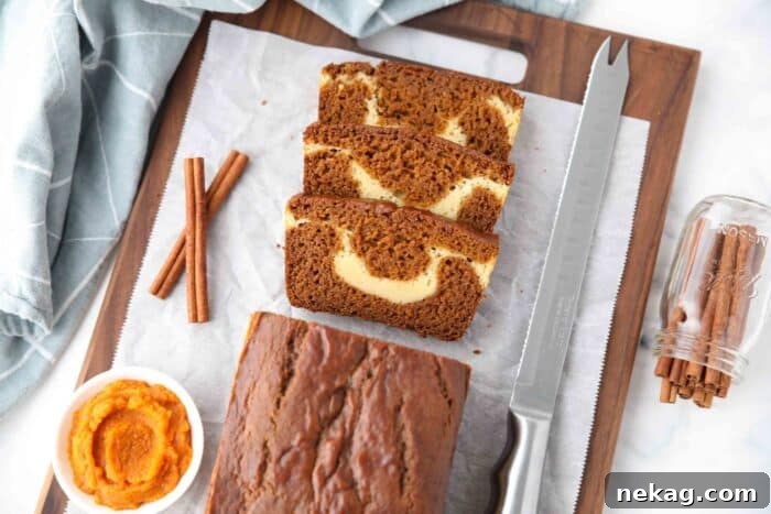 Swirled Pumpkin Cream Cheese Bread 10 A loaf of pumpkin cream cheese bread with a few slices cut, showing a swirl of cream cheese in the center.