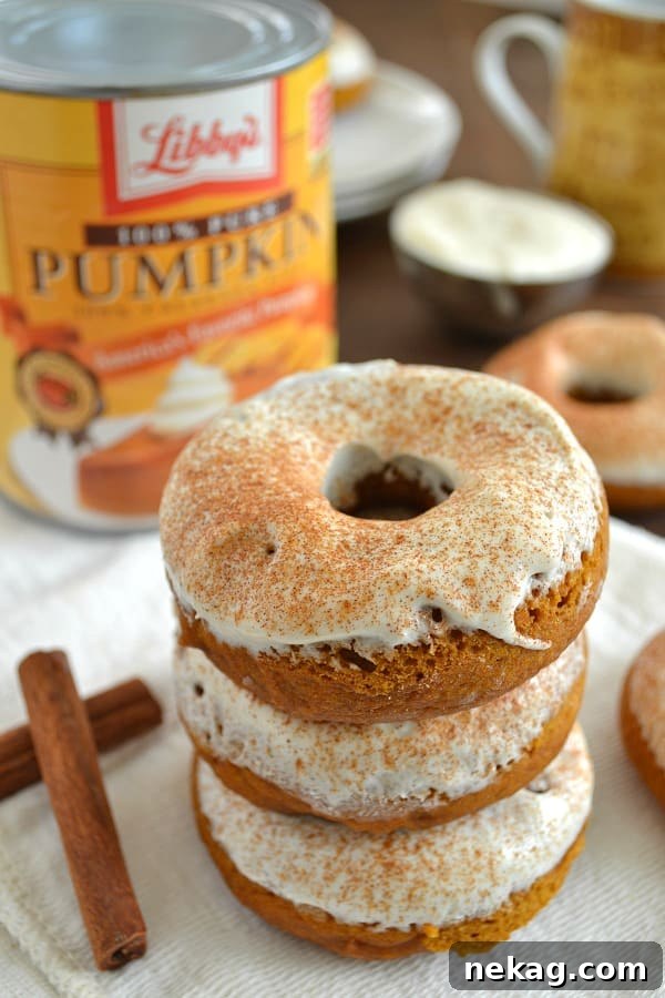 Decadent Pumpkin Spice Cheesecake Donuts 5 Hand holding a Pumpkin Spice Cheesecake Donut, showing its soft interior.