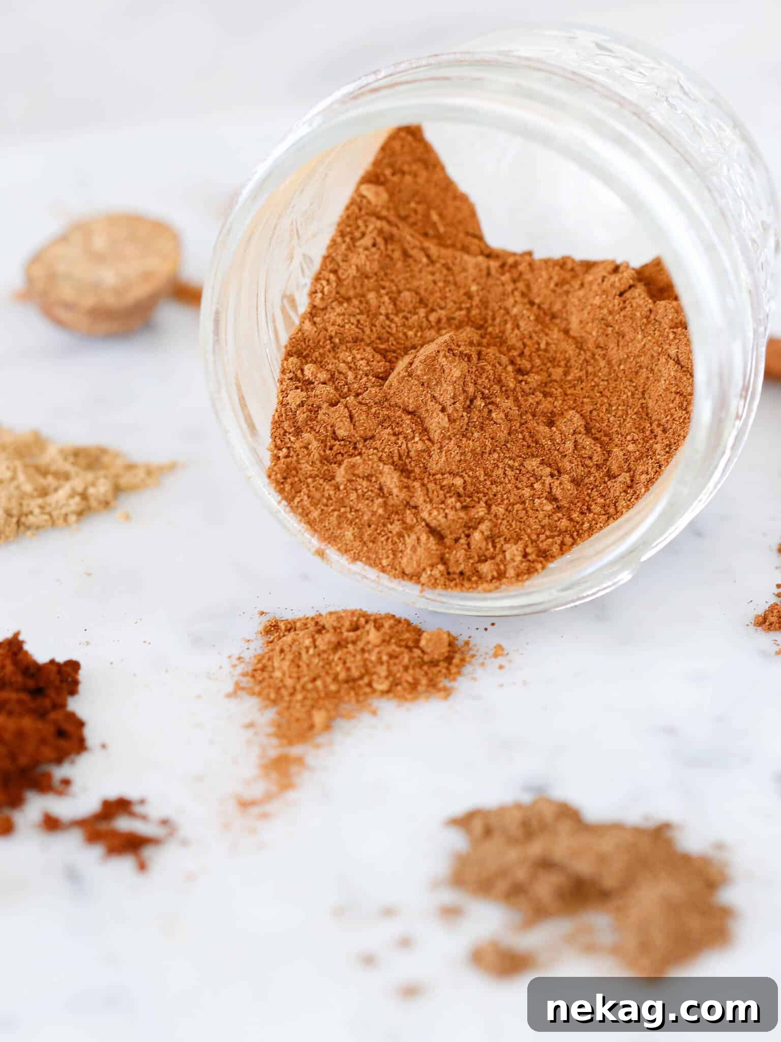 Pumpkin Spice Delights 2 Homemade pumpkin spice mix spilling out of a glass jar, showcasing its rich, warm colors.