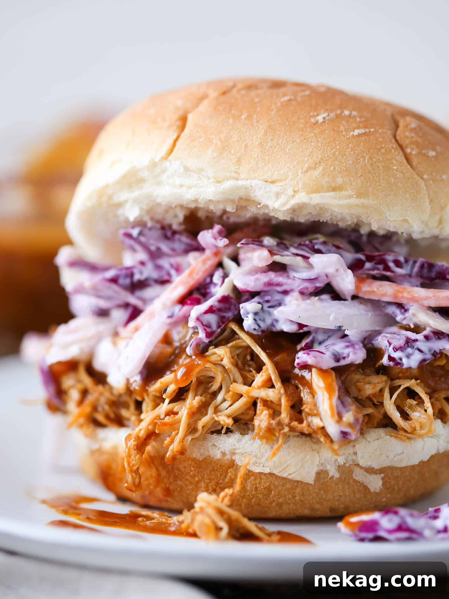 Mouthwatering Slow Cooker Barbecue Pulled Chicken on a bun with fresh coleslaw.