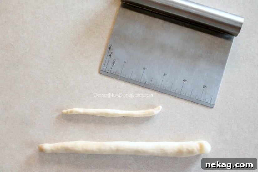 A long rope of dough for the broomstick handle and a smaller piece for the broom's wrapping, both rolled out.