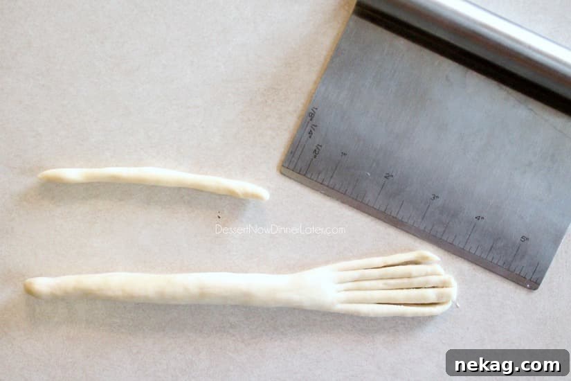 A small dough rope being wrapped around the base of the broomstick bristles.