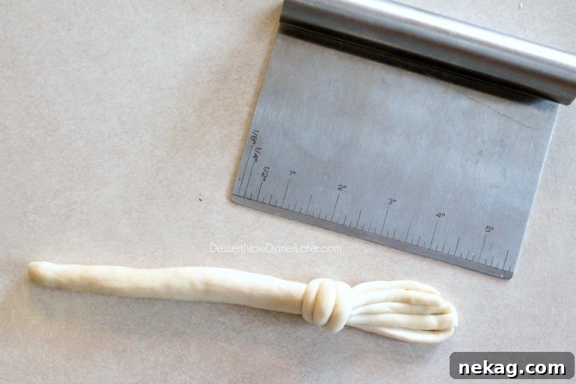 Multiple Witch's Broomstick Breadsticks lined up on a baking sheet, ready for baking.
