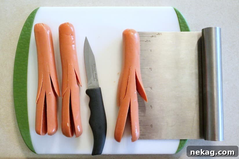 A close-up of hot dogs with pre-cut slits forming 'arms' and 'legs', demonstrating where to make the cuts for the mummy shape, with a ruler showing approximate measurements.