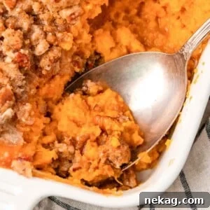 Sweet potato casserole being served onto a plate, highlighting its creamy texture and crunchy pecan topping.