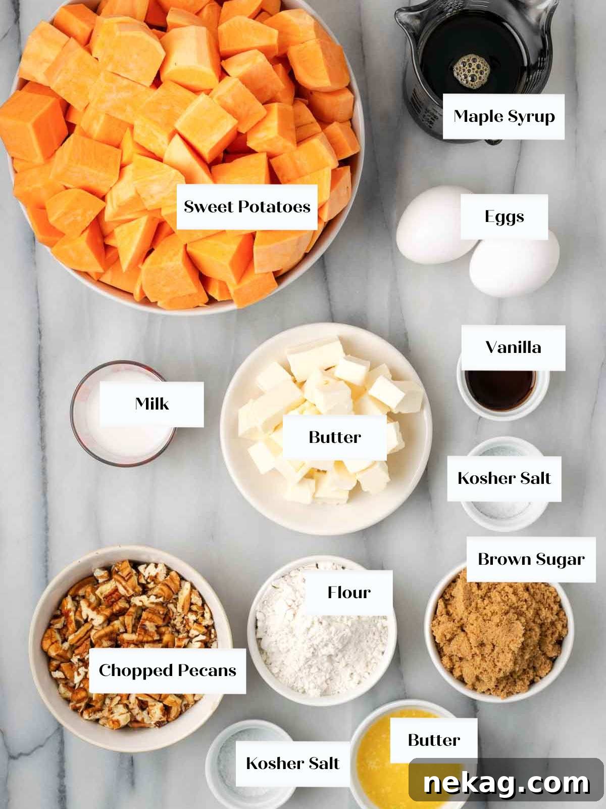 Assortment of fresh sweet potato casserole ingredients laid out on a marble surface: sweet potatoes, maple syrup, eggs, vanilla, milk, butter, salt, brown sugar, flour, and pecans.