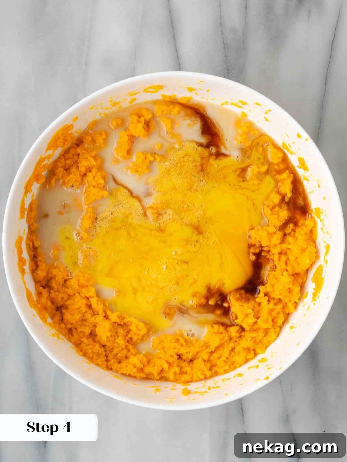 The sweet potato casserole base ingredients, including maple syrup and eggs, being mixed in a bowl.
