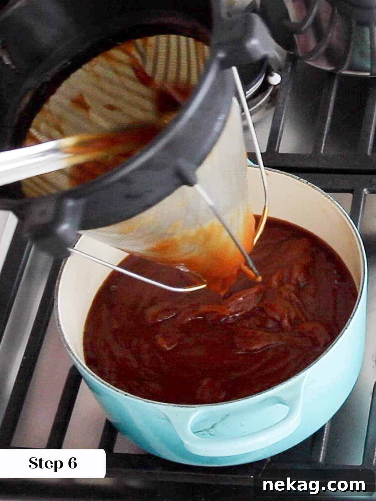 Straining pureed apple butter through a fine-mesh chinoise strainer to achieve a smooth texture.