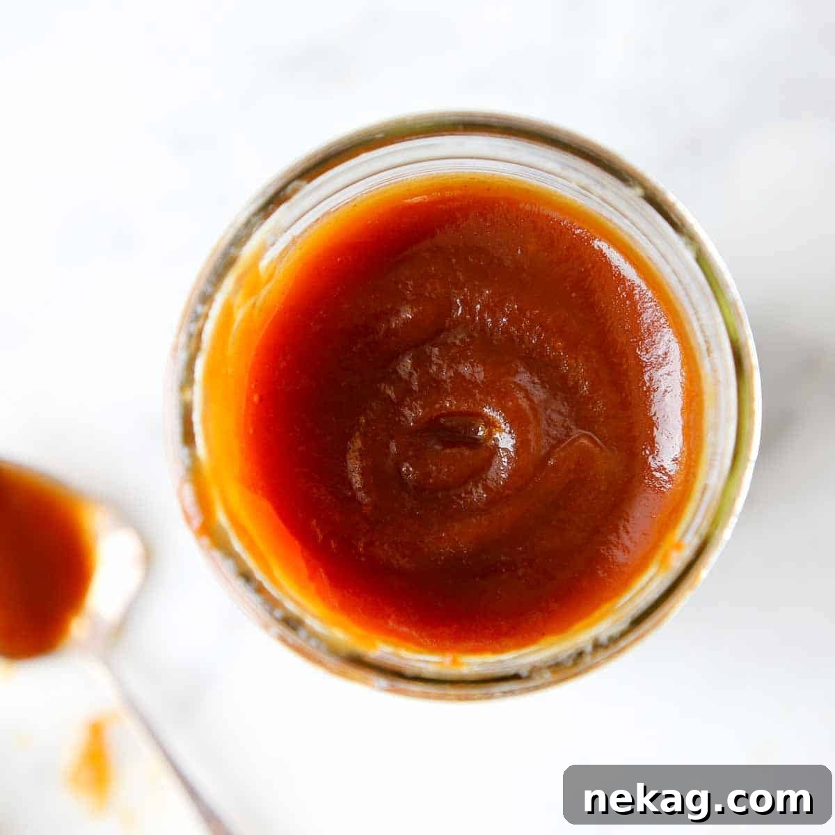 Apple butter beautifully swirled in a mason jar, showcasing its smooth texture and rich color.