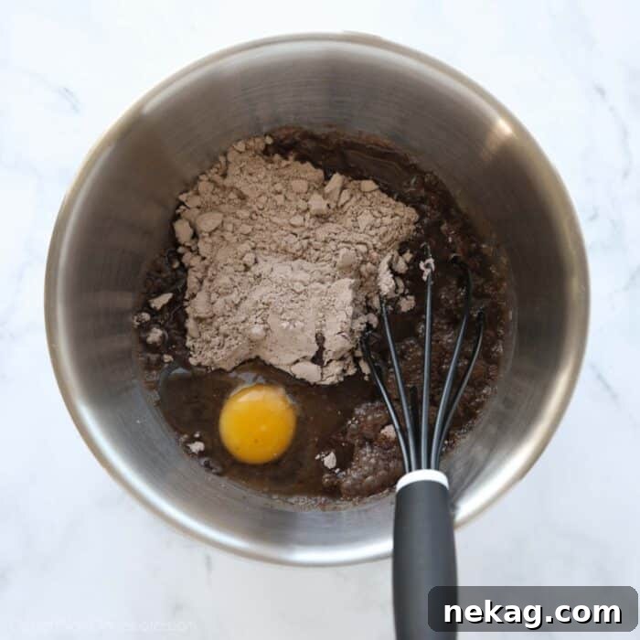 Fudgy Cookies and Cream Brownies 6 A large mixing bowl containing brownie ingredients like mix, eggs, water, and oil, being whisked together to create a smooth, rich batter, ready for the next step of baking.