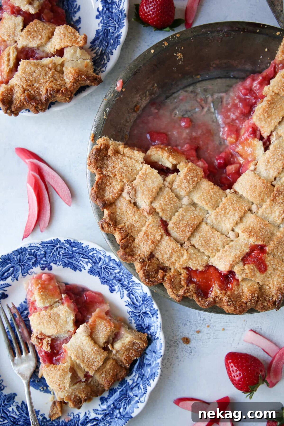 Strawberry Rhubarb Delight 2 A stunning Strawberry Rhubarb Pie in an almond lattice crust, with two slices perfectly arranged on elegant blue plates, ready to be served and enjoyed.