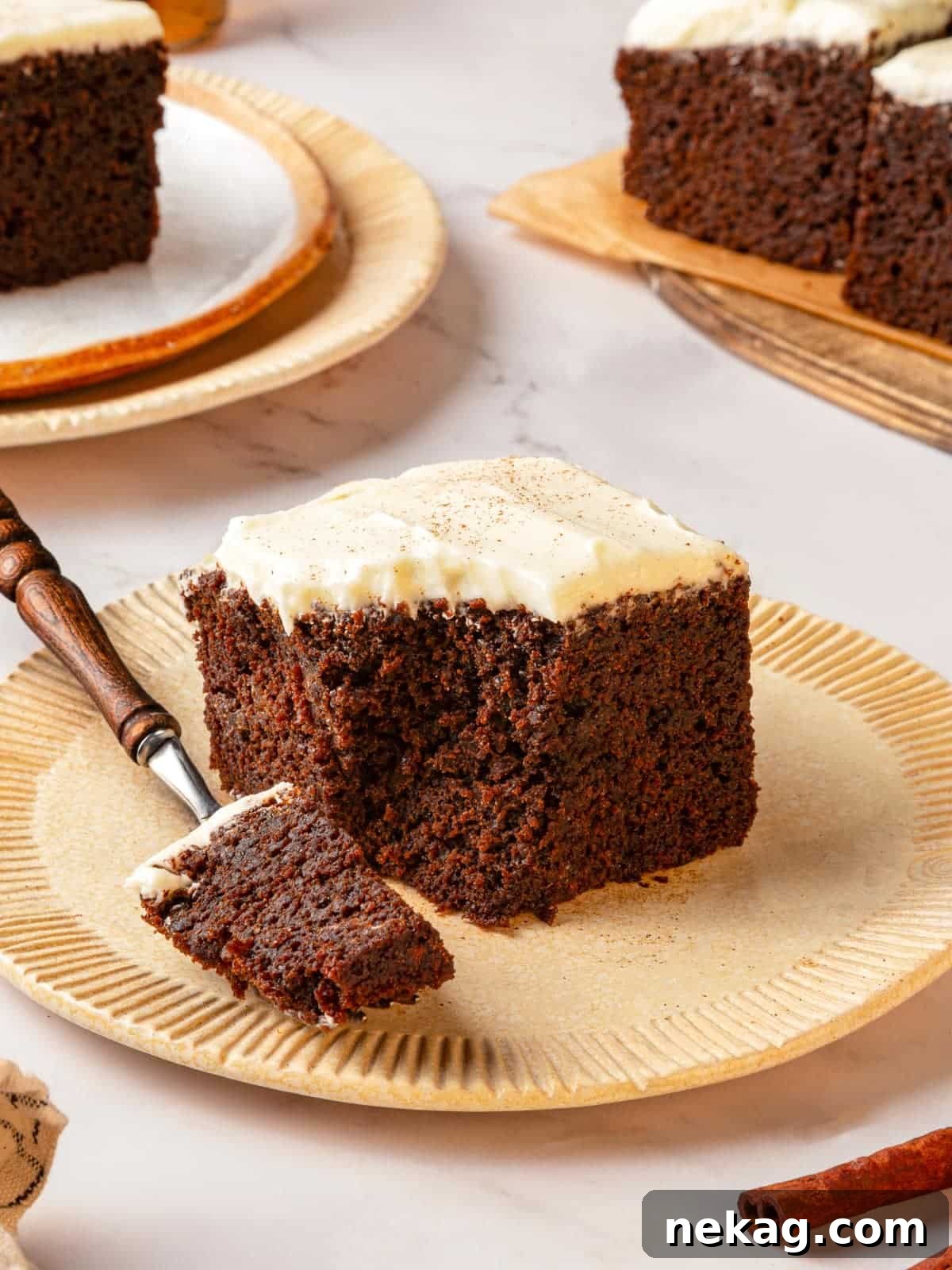 Fork holding a bite of gingerbread cake on the plate to show texture clearly. The cake is moist and fluffy.