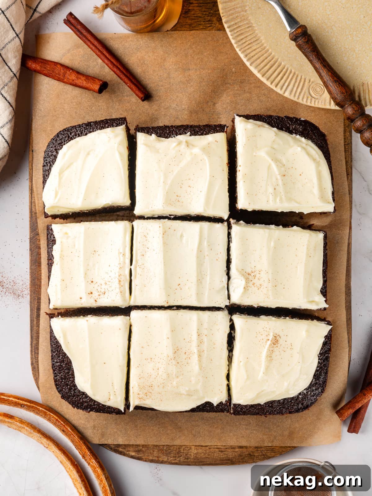 Frosted gingerbread cake cut into squares with creamy topping spread evenly across the surface.