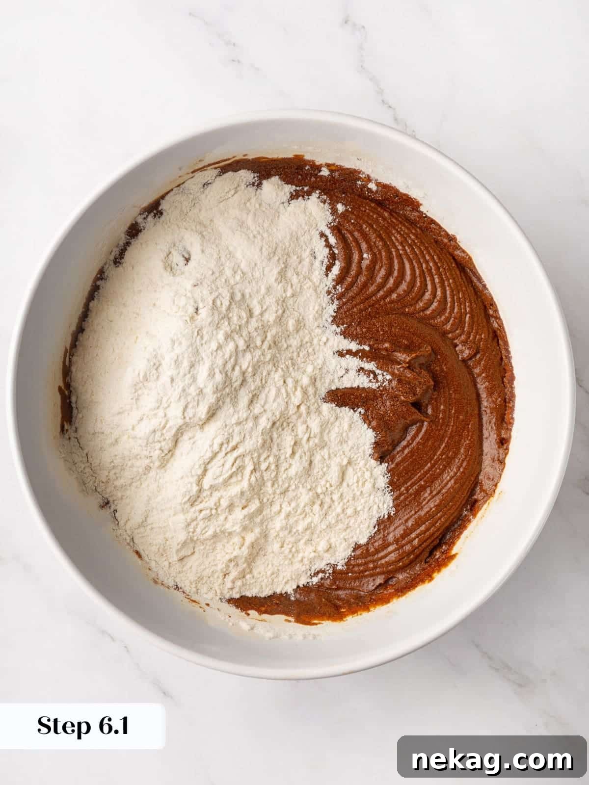 Spiced flour mixture being added into the wet gingerbread batter during mixing.