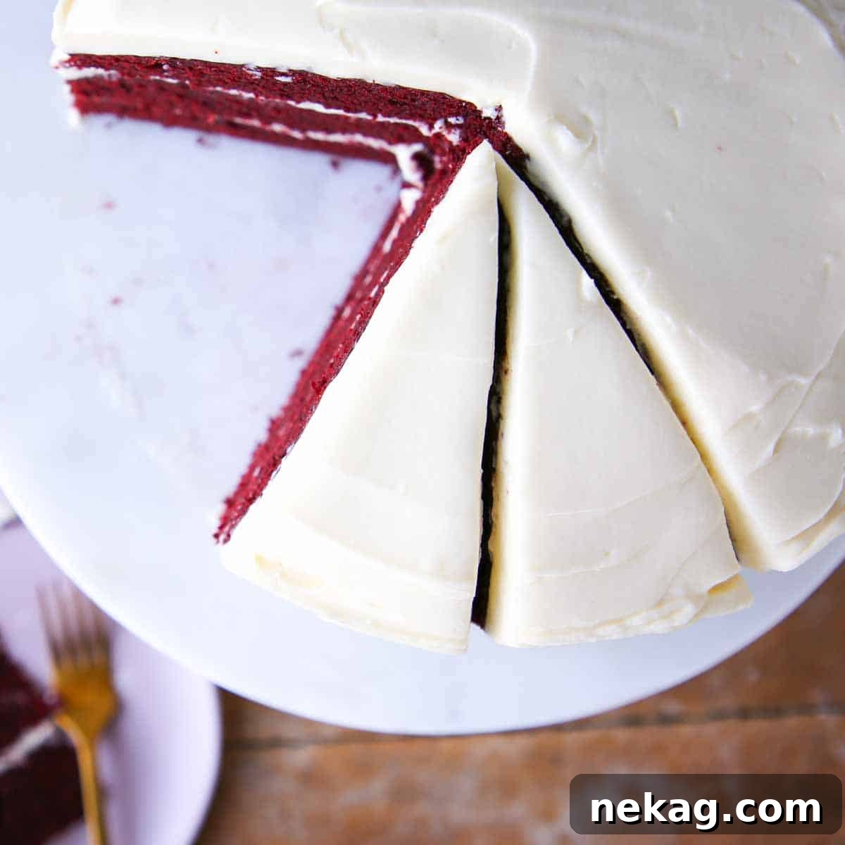 Red velvet cake slice with bourbon cream cheese buttercream on a marble cake stand.
