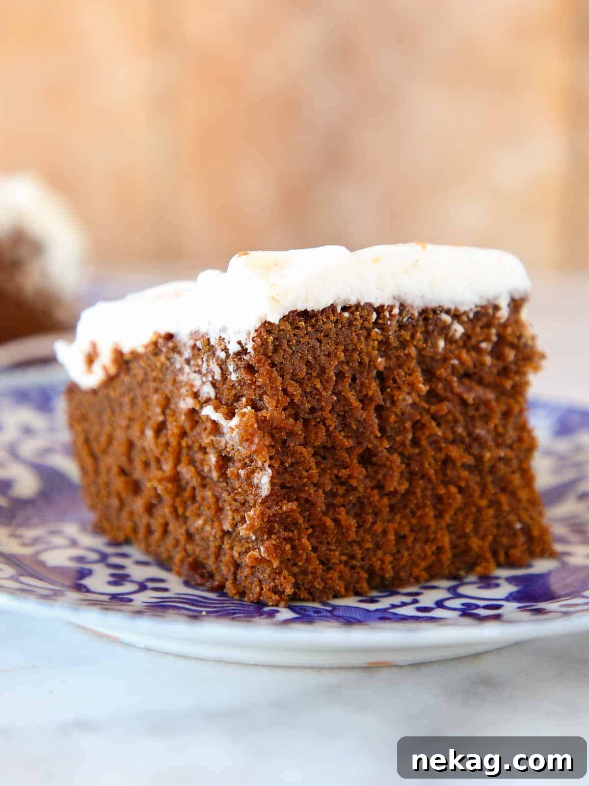 Gingerbread cake slice with cream cheese frosting on a blue plate.