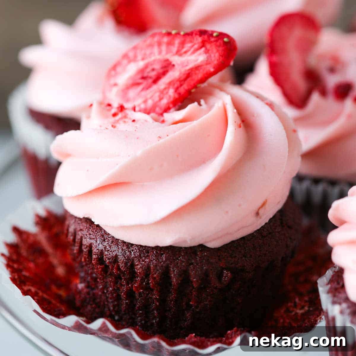 Red velvet cupcake with strawberry cream cheese buttercream and a fresh strawberry on top.