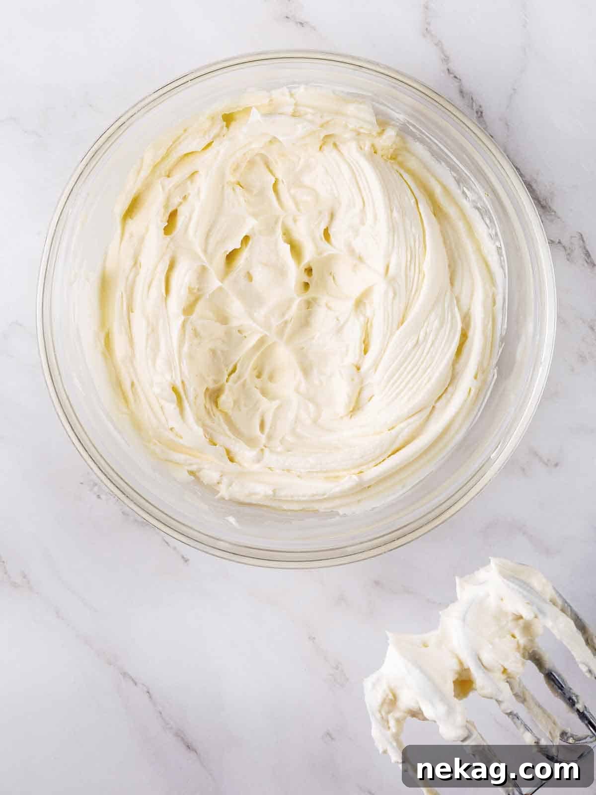 Cream cheese buttercream frosting in a mixing bowl with beaters.